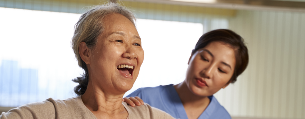 A woman smiling with a healthcare professional beside her